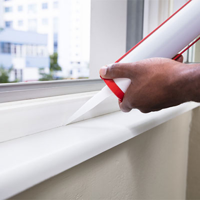 person applying adhesive product to window